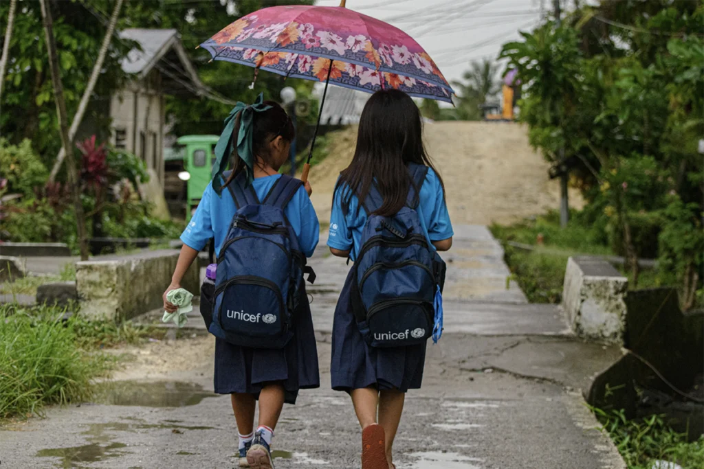crianças indo para escola com gurada-chuva