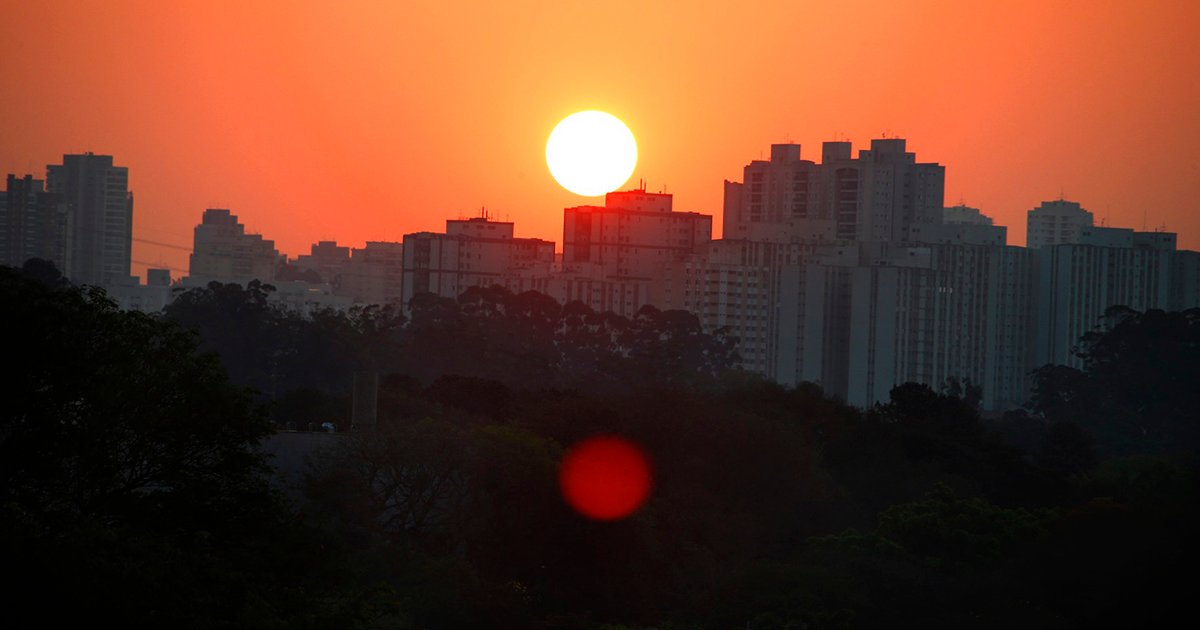 Horizonte de uma cidade com prédios e ao fundo o sol e um céu avermelhado